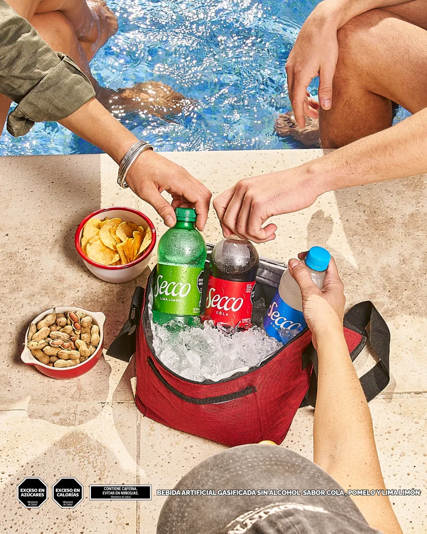 Manos tomando Secco Lima Limón, Cola y Pomelo de una heladerita con hielo junto a la pileta